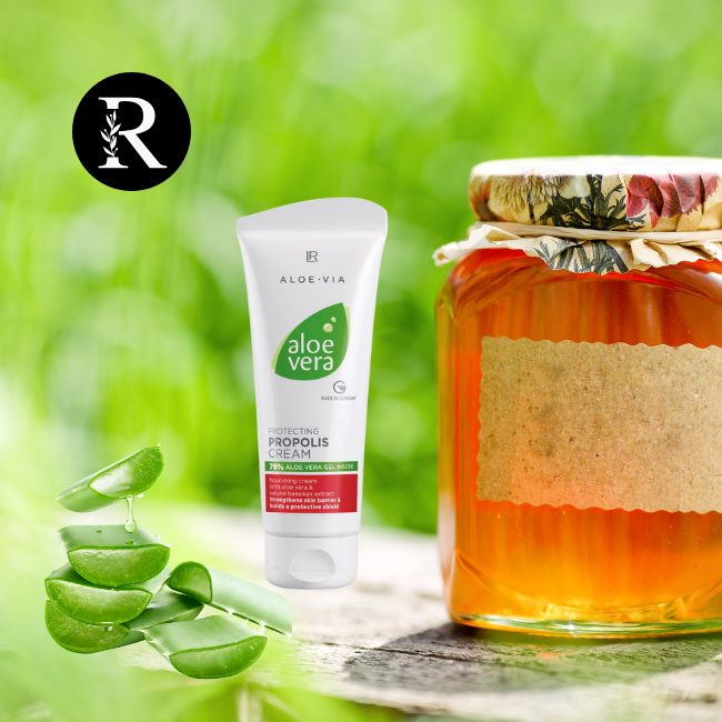 Composición natural que incluye un tarro de miel decorado, una crema de aloe vera con propóleo LR y hojas de aloe vera frescas, dispuestas sobre una superficie de madera en un entorno verde al aire libre. El logotipo de Natural Radiance Cosmetics aparece en la esquina superior izquierda.